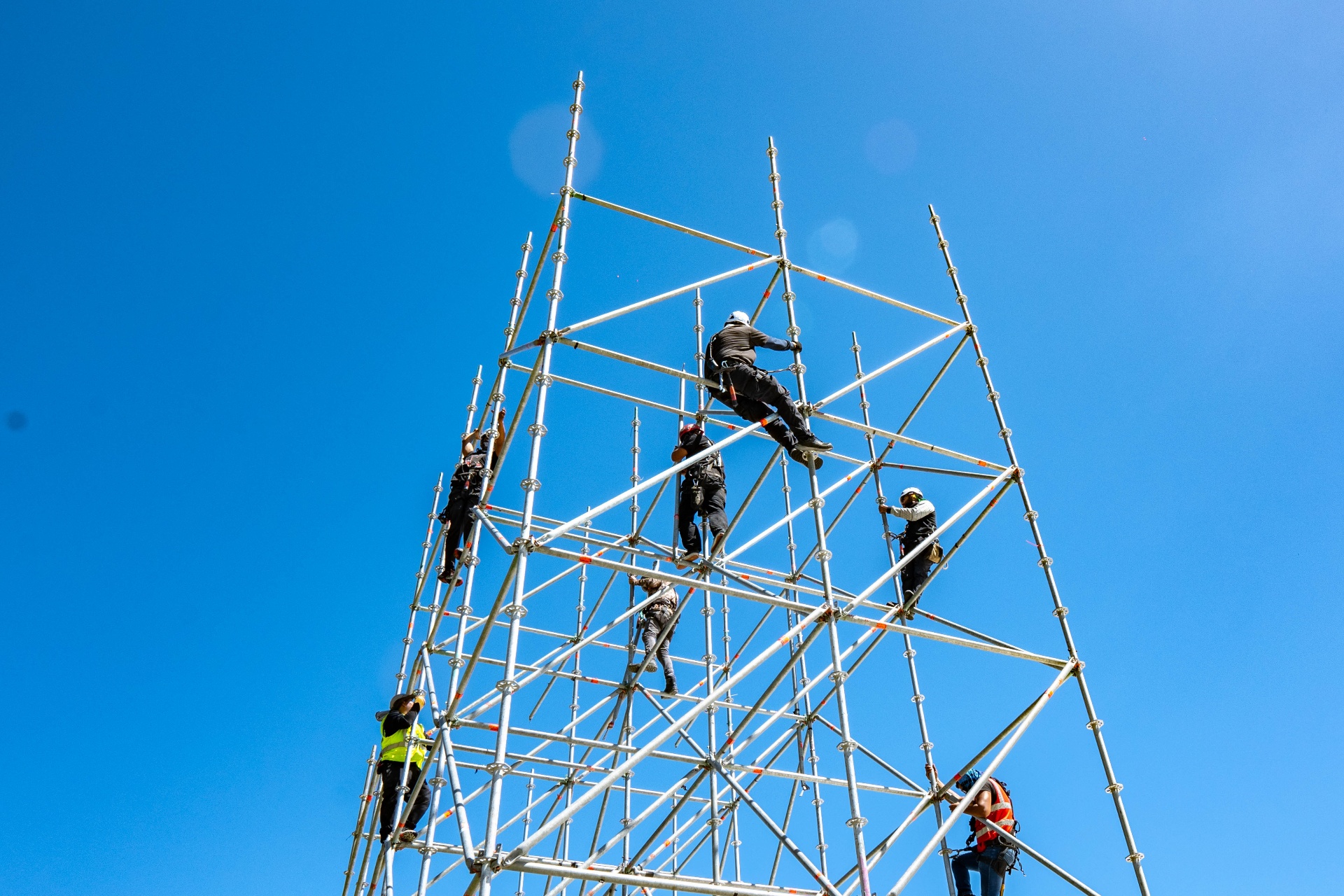 Scaffolding tower being assembled against a blue sky.