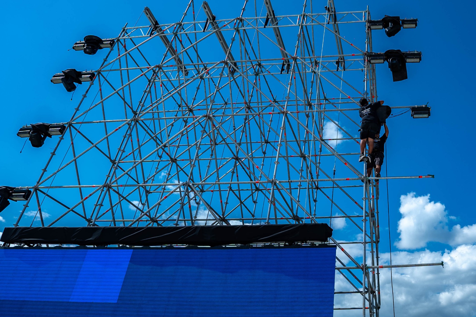Technicians installing lighting fixtures on the main truss.